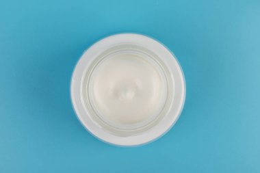 Mavi arka planda nemlendirici yüz kremi kabı. Moda kadını hala hayatta. Pop kadın şeyleri, ilaç ve kozmetik tema.