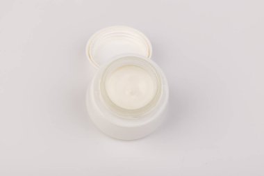 Beyaz arka planda nemlendirici yüz kremi kabı. Moda kadını hala hayatta. Pop kadın şeyleri, ilaç ve kozmetik tema.