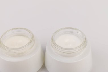 Beyaz arka planda nemlendirici yüz kremi kabı. Moda kadını hala hayatta. Pop kadın şeyleri, ilaç ve kozmetik tema.