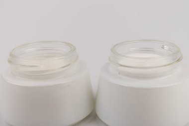 Beyaz arka planda nemlendirici yüz kremi kabı. Moda kadını hala hayatta. Pop kadın şeyleri, ilaç ve kozmetik tema.