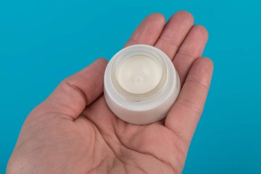 Mavi arka planda nemlendirici yüz kremi kabı. Moda kadını hala hayatta. Pop kadın şeyleri, ilaç ve kozmetik tema.