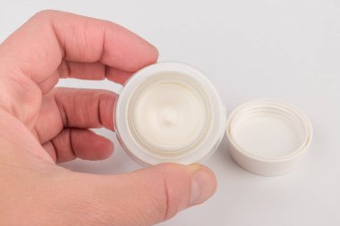 Beyaz arka planda nemlendirici yüz kremi kabı. Moda kadını hala hayatta. Pop kadın şeyleri, ilaç ve kozmetik tema.