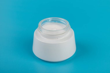 Mavi arka planda nemlendirici yüz kremi kabı. Moda kadını hala hayatta. Pop kadın şeyleri, ilaç ve kozmetik tema.