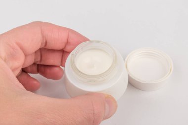 Beyaz arka planda nemlendirici yüz kremi kabı. Moda kadını hala hayatta. Pop kadın şeyleri, ilaç ve kozmetik tema.