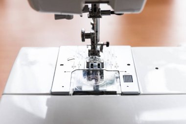 Dikiş bezi için endüstriyel dikiş makinesinin koyu ipliğine sahip iğne basan ayak ve fotokopi alanı yakın plan ile bulanık bokeh arkaplan.