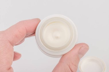 Beyaz arka planda nemlendirici yüz kremi kabı. Moda kadını hala hayatta. Pop kadın şeyleri, ilaç ve kozmetik tema.