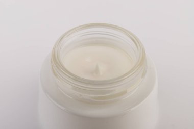 Beyaz arka planda nemlendirici yüz kremi kabı. Moda kadını hala hayatta. Pop kadın şeyleri, ilaç ve kozmetik tema.