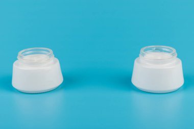 Mavi arka planda nemlendirici yüz kremi kabı. Moda kadını hala hayatta. Pop kadın şeyleri, ilaç ve kozmetik tema.