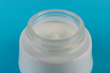 Mavi arka planda nemlendirici yüz kremi kabı. Moda kadını hala hayatta. Pop kadın şeyleri, ilaç ve kozmetik tema.