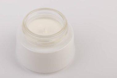 Beyaz arka planda nemlendirici yüz kremi kabı. Moda kadını hala hayatta. Pop kadın şeyleri, ilaç ve kozmetik tema.