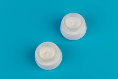 Mavi arka planda nemlendirici yüz kremi kabı. Moda kadını hala hayatta. Pop kadın şeyleri, ilaç ve kozmetik tema.