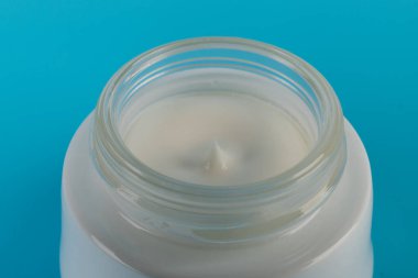 Mavi arka planda nemlendirici yüz kremi kabı. Moda kadını hala hayatta. Pop kadın şeyleri, ilaç ve kozmetik tema.