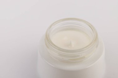 Beyaz arka planda nemlendirici yüz kremi kabı. Moda kadını hala hayatta. Pop kadın şeyleri, ilaç ve kozmetik tema.