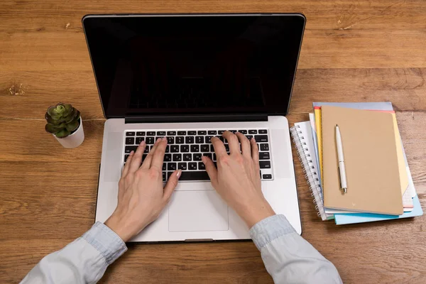 Woman working with laptop on old wood table. Mix of office supplies and gadgets on a wooden desk background. copy space.