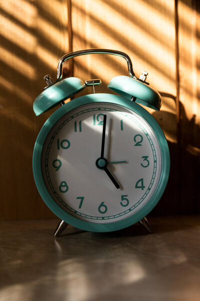 Beautiful retro blue pastel alarm clock on wooden background. time to act concept