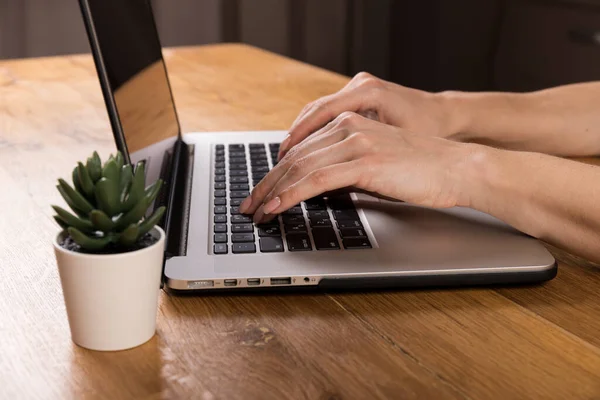 Woman working with laptop on old wood table. Mix of office supplies and gadgets on a wooden desk background. copy space.