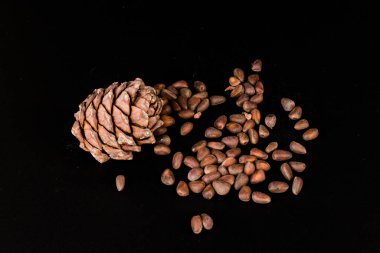 Kabukta sedir fıstığı ve siyah arka planda izole edilmemiş kozalaklar.