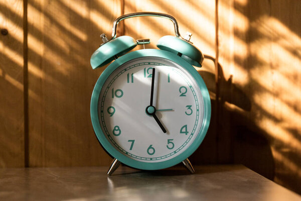 Beautiful retro blue pastel alarm clock on wooden background. time to act concept