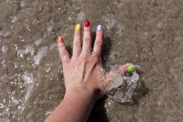 Colorful nail art on sand beach. Colorful nail polish. concept of the summer rest