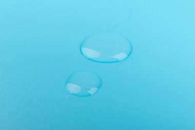 Kozmetik ya da tıbbi serum mavi arka planda, yakın planda düşer. Cilt bakımı kavramı. 