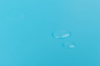 Kozmetik ya da tıbbi serum mavi arka planda, yakın planda düşer. Cilt bakımı kavramı. 