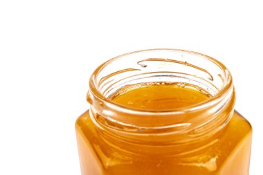 Cam kavanozdaki bal, beyaza yakın plan. İzole edilmiş.