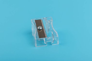 Kırtasiye malzemeleri, okul malzemeleri, ofiste çalışmak ve yaratıcılık, metal bıçaklı şeffaf kalem açacağı, mavi arka planda izole edilmiş.