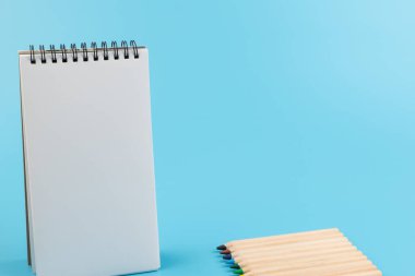 çok renkli kalemler ve mavi arkaplandaki boş defter kopyalama alanı ile