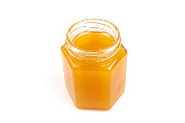 Cam kavanozdaki bal, beyaza yakın plan. İzole edilmiş.