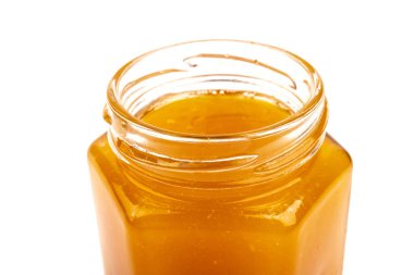 Cam kavanozdaki bal, beyaza yakın plan. İzole edilmiş.