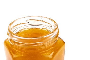 Cam kavanozdaki bal, beyaza yakın plan. İzole edilmiş.