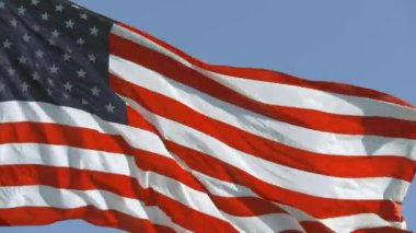 Mavi gökyüzüyle rüzgarda dalgalanan Amerikan Bayrağı