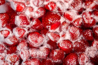 Ev yapımı çilek reçeli kaynama aşamasında. Ev yapımı çilek reçeli yapma süreci. Kırmızı tatlı şurup ocakta kaynıyor..