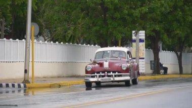 1950 Pontiac Silver 8 Serisi. Antika kiraz çiçekleri, eski arabalar yağmurlu bir günde Küba tatil köyünün merkez caddesi boyunca sürüyorlar. Kırmızı bir vintage taksinin yakın çekimi. Varadero, Küba - 14 Ocak 2022