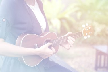 Güzel kadın ukulele oynamak okuyan.