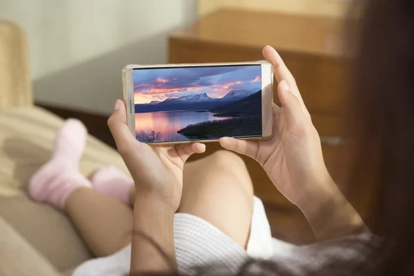 Güzel kadın sabah ları mutlu bir şekilde yatakta telefon çalıyor. O cep telefonu İsveç manzaraları bakıyordu.