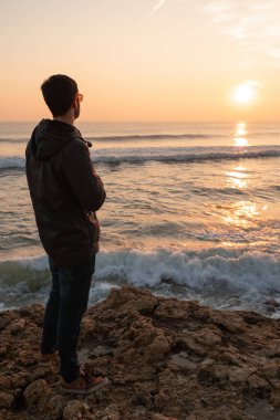 Güneş gözlükleriyle gün batımına bakan adam güneşli bir günde Portekiz 'de Atlantik Okyanusu' nda