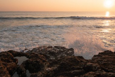 Güneşli bir günde Portekiz 'de Atlantik Okyanusu' nda gün batımı ve dalgalar kırılıyor.