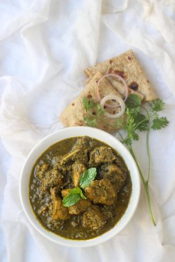 Beyaz arka planda naan veya chapati ile servis edilen yeşil kişniş tavuğu körisi. 