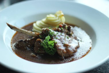 Beyaz tabakta servis edilen patates püresi ve körili lamba. Estetik ruh hali aydınlatmalı.