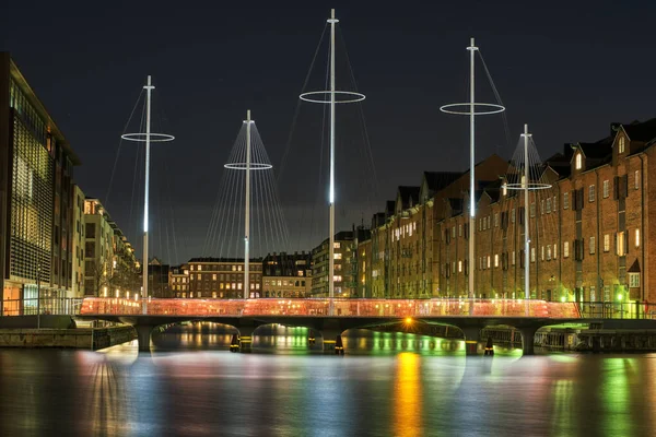 エリアソン サーケルブローン 5つの円歩行者橋 が市内の近代的な住宅地で夜に照明された運河を渡っている 水の上で光を再生すると 居心地の良い街並みの雰囲気と水の光の反射になります デンマークのコペンハーゲン ストック写真