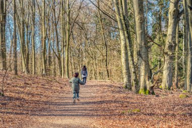 Anne ve oğlu çıplak bir ormanda gezip tozuyor. Yürüyen annesinin peşinden ormanda serbestçe koşan bir çocuk. Ormanda ya da ağaçların arasında özgürce dolaşan bir çocukla aile günü.