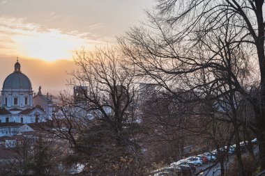 İtalyan mimarisi ve doğa: Colle Cidneo 'da yapraksız orman. Cattedrale Santa Maria Assunta (St Mary Katedrali) kubbesi ile şehir, gün batımında şehrin siluetine hakim olur - Brescia, İtalya