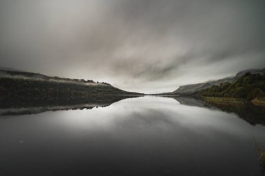 Glencar Lough göldeki alçak bulutların yansıması Benbulbin dağı sisin ortasında suya giriyor. Bulutlu gökyüzü kasvetli, kasvetli ve kasvetli hisleri iletiyor - County Sligo, İrlanda