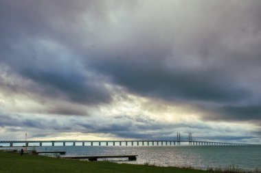 Baltık Denizi 'ndeki Öresund Köprüsü Sibbarp, Limhamn' dan bulutlu ve dramatik bir gökyüzüne karşı ele geçirildi. Oresundsbron (Oresundsbroen), İsveç ve Danimarka arasında Oresund Boğazı boyunca bir bağlantıdır.