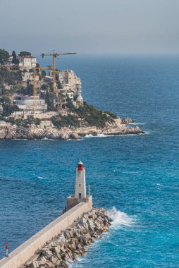 Port Lympia 'daki Phare de Nice Deniz feneri rıhtımına çarpan dalgaları tasvir eden Colline du Chateau (Castle Hill)' den Güzel Burun ve Fransa 'nın kayalıkları