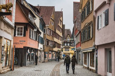 Tubingen, Almanya - 24 Aralık 2017 Dar kaldırımlı sokaklarda sessiz bir atmosfer. Geleneksel Alman ahşabı ya da yarı ahşap çatısı ya da eğimli çatısı olan binalar, dükkanlar ve Tubingen Ortaçağ 'da çekilmiş insanlar.