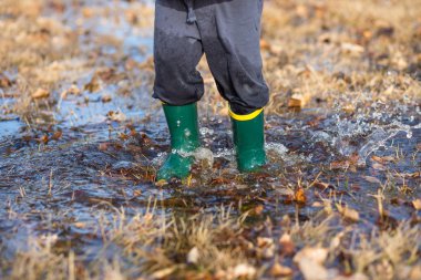 Toddler jumping in puddles wearing rainboots clipart