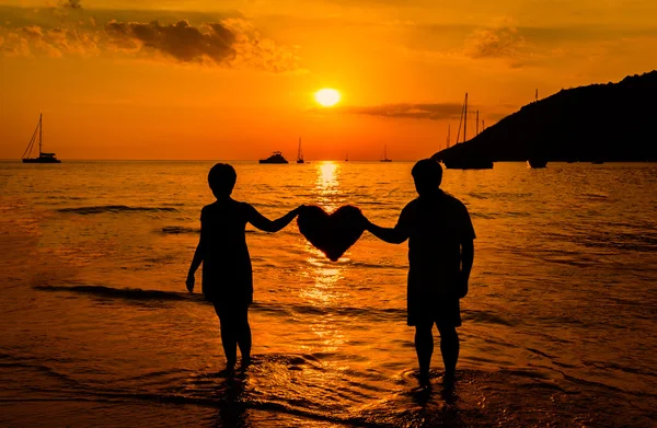 Silueta páru na pláži při západu slunce — Stock fotografie