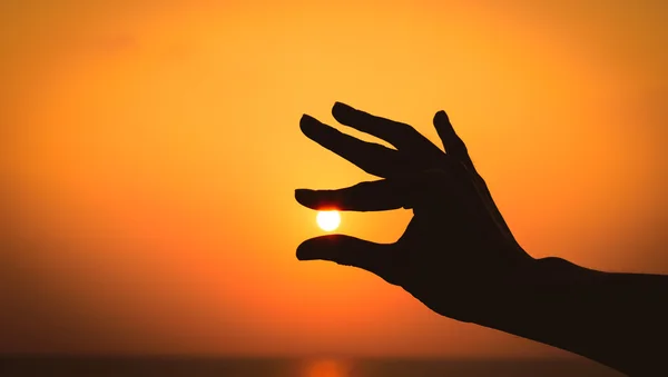 Силуэт Мужская рука держит солнце на закате . — стоковое фото